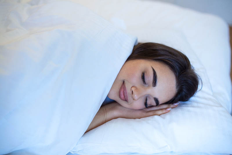 Young caucasian woman sleeping in the bed relaxed calm dreams